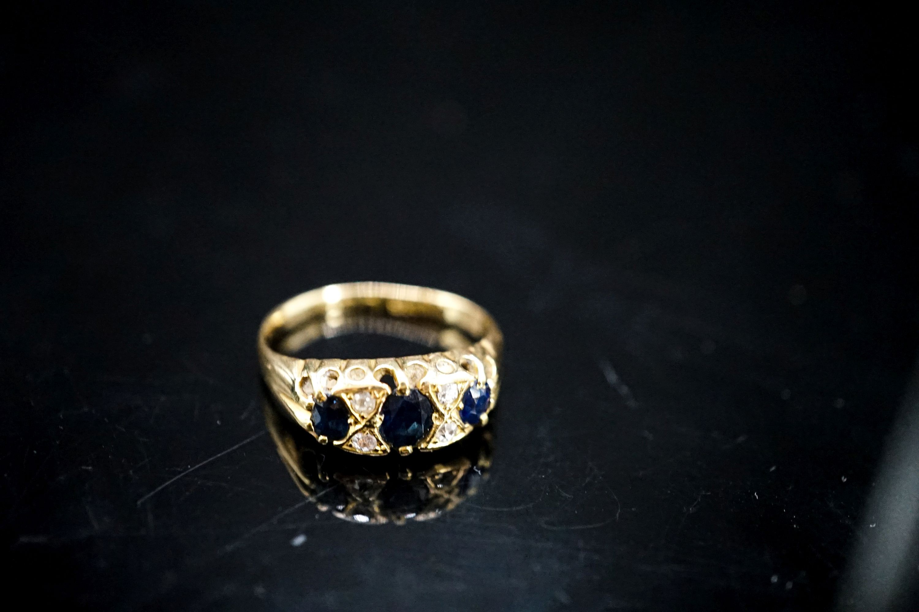 A late Victorian 18ct gold, three stone sapphire and four stone diamond chip set ring, size L, gross weight three grams.